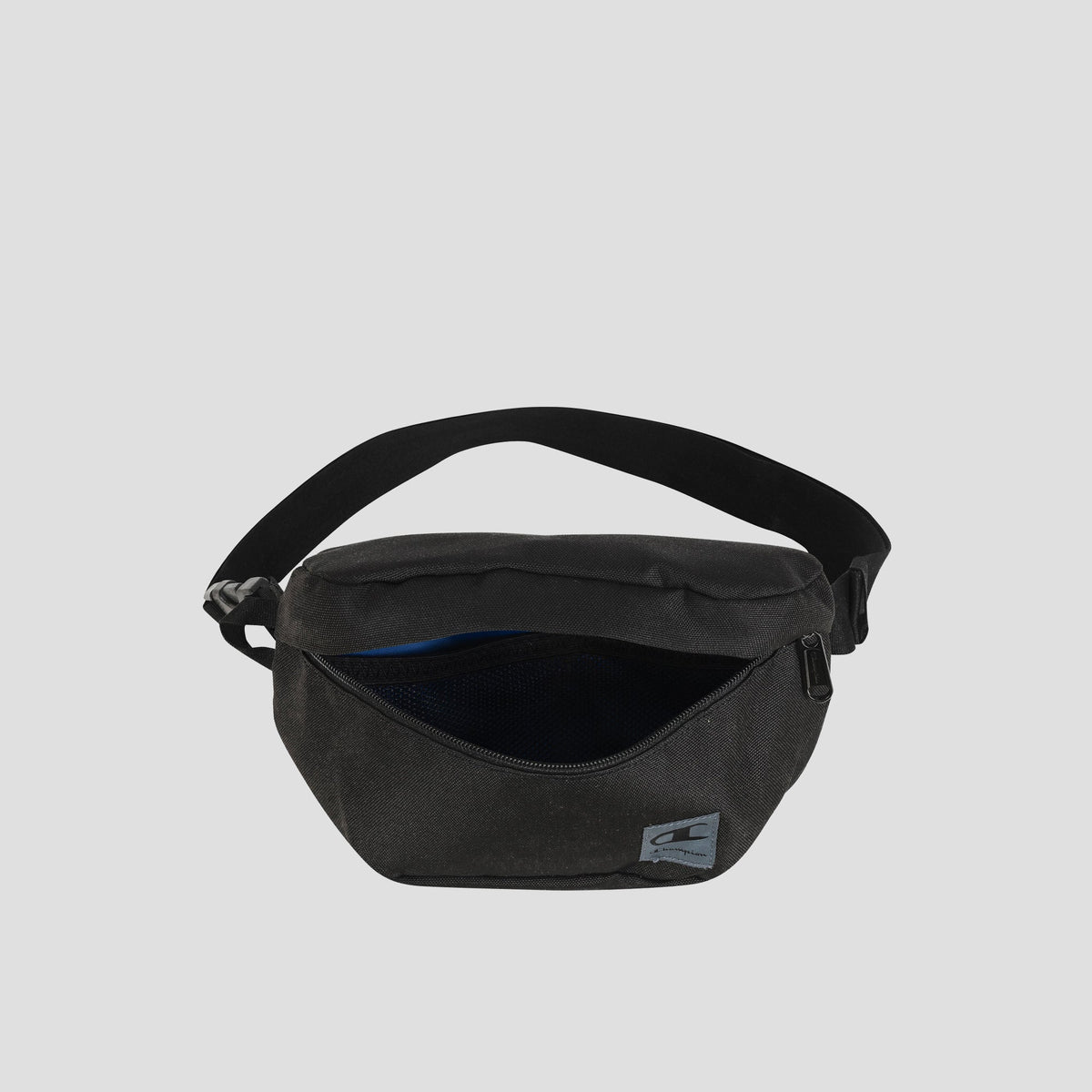 The Champion Atlas Waist Pack in black features a zippered main compartment that is partially open to reveal an inner mesh pocket. This bag includes an adjustable strap, adventure-ready storage for your essentials, and a small rectangular Champion logo patch on the front.