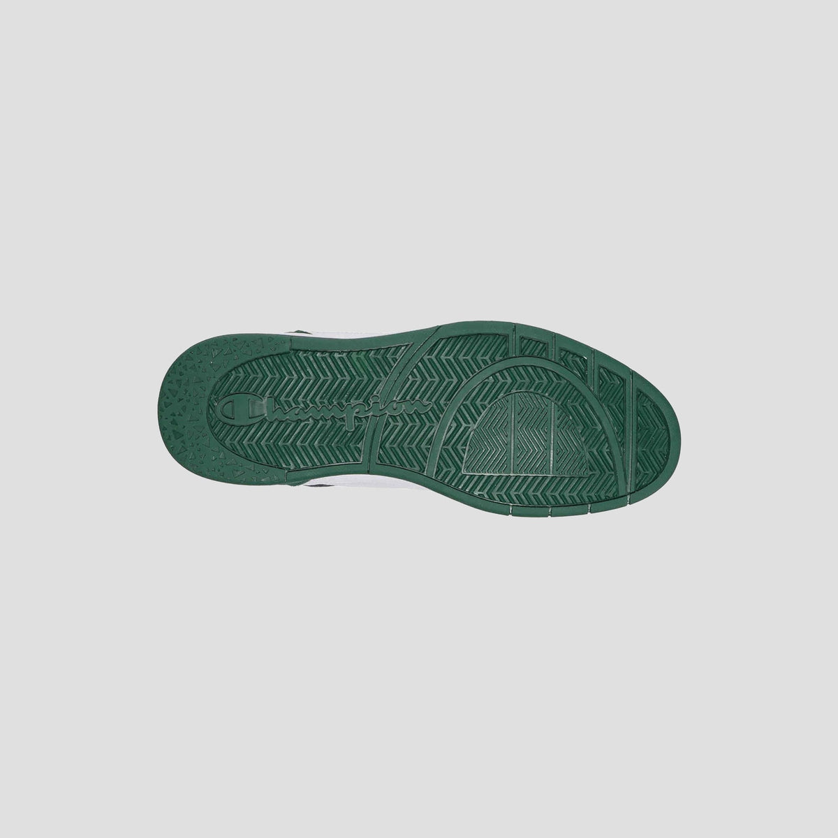 A green rubber sole of the Champion Men's 5-on-5 Low sneaker is shown from below, revealing its textured tread with lines and geometric shapes, emphasizing the minimalist style against a plain light gray background.