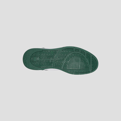 A green rubber sole of the Champion Men's 5-on-5 Low sneaker is shown from below, revealing its textured tread with lines and geometric shapes, emphasizing the minimalist style against a plain light gray background.