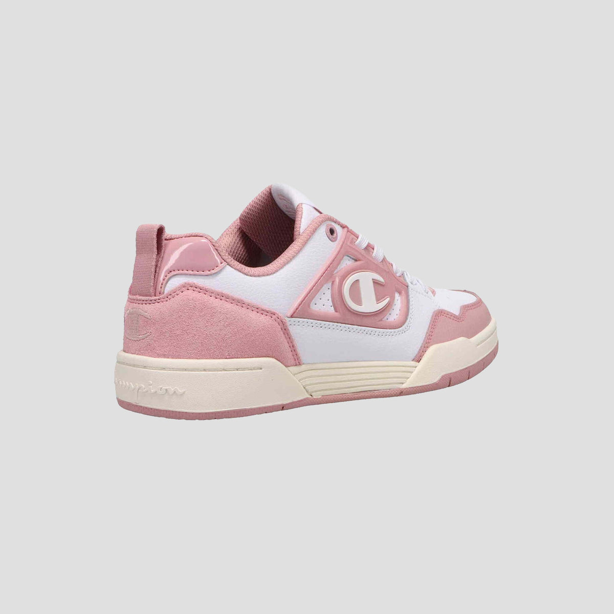 The Champion Women's 5-on-5 Low is a pink and white suede and leather sneaker with a cushioned collar, white laces, large C logo, and an off-white sole with pink details. Shown on a plain gray background.