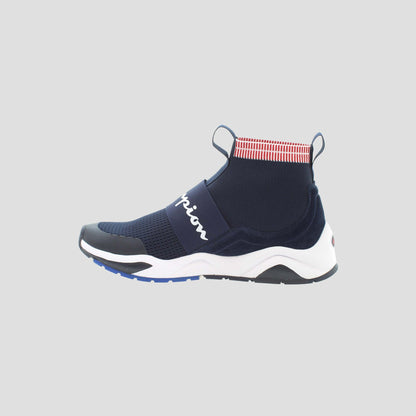 The Champion Men's Rally Pro is a navy blue slip-on sneaker featuring a cushioned insole, white sole, black toe cap, red and white striped ankle collar, and a white script logo on the side, shown on a light gray background.