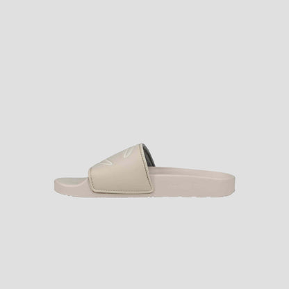 The Champion Women's IPO Slide is a beige sandal with a wide strap and open toe, offering lightweight comfort and a contoured footbed, shown on a plain light gray background.