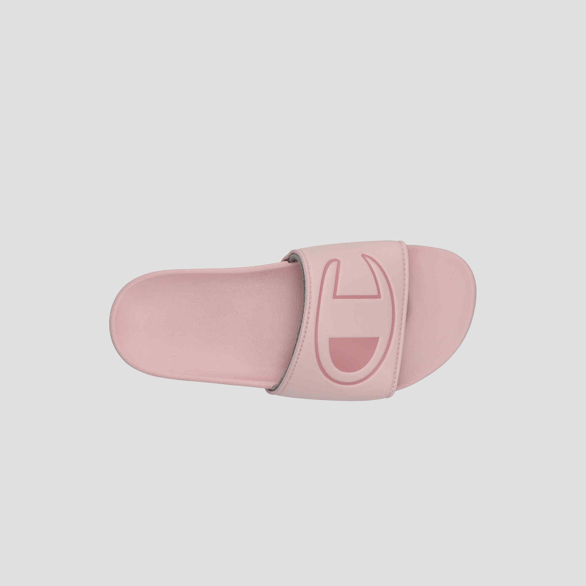 The Champion Women's IPO Slide is a pink slide sandal with a wide strap and large embossed logo. Viewed from above on a light background, its contoured footbed ensures extra comfort for supportive, stylish wear.