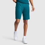 A person wearing Champion 10″ Moisture Wicking Sport Shorts in teal, a matching teal shirt, white socks, and white sneakers stands against a plain light gray background. Their face is not visible.