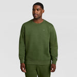 A man wearing an olive green Powerblend Crewneck Sweatshirt, C Logo - Big & Tall with a small logo on the chest and matching sweatpants.
