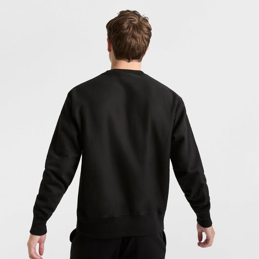 A person with short brown hair is shown from the back wearing a Champion Reverse Weave Crewneck Sweatshirt, C Logo, and black heavyweight fleece pants against a white background.