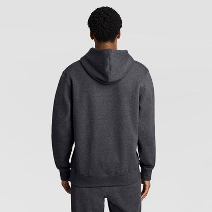 A person wearing the Champion Powerblend Hoodie, Full Script Logo in dark gray with matching pants is shown from the back, standing against a plain light gray background.