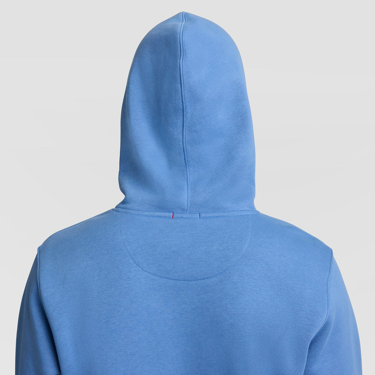 A person is shown from the back, wearing the Champion Powerblend Hoodie, Full Script Logo in light blue with the hood up, set against a plain light background.