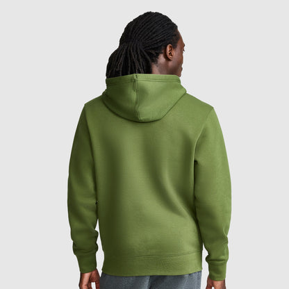 A person with long, dark hair is shown from the back, wearing a Champion Powerblend Hoodie with Full Script Logo in green and gray pants, standing against a plain light gray background.
