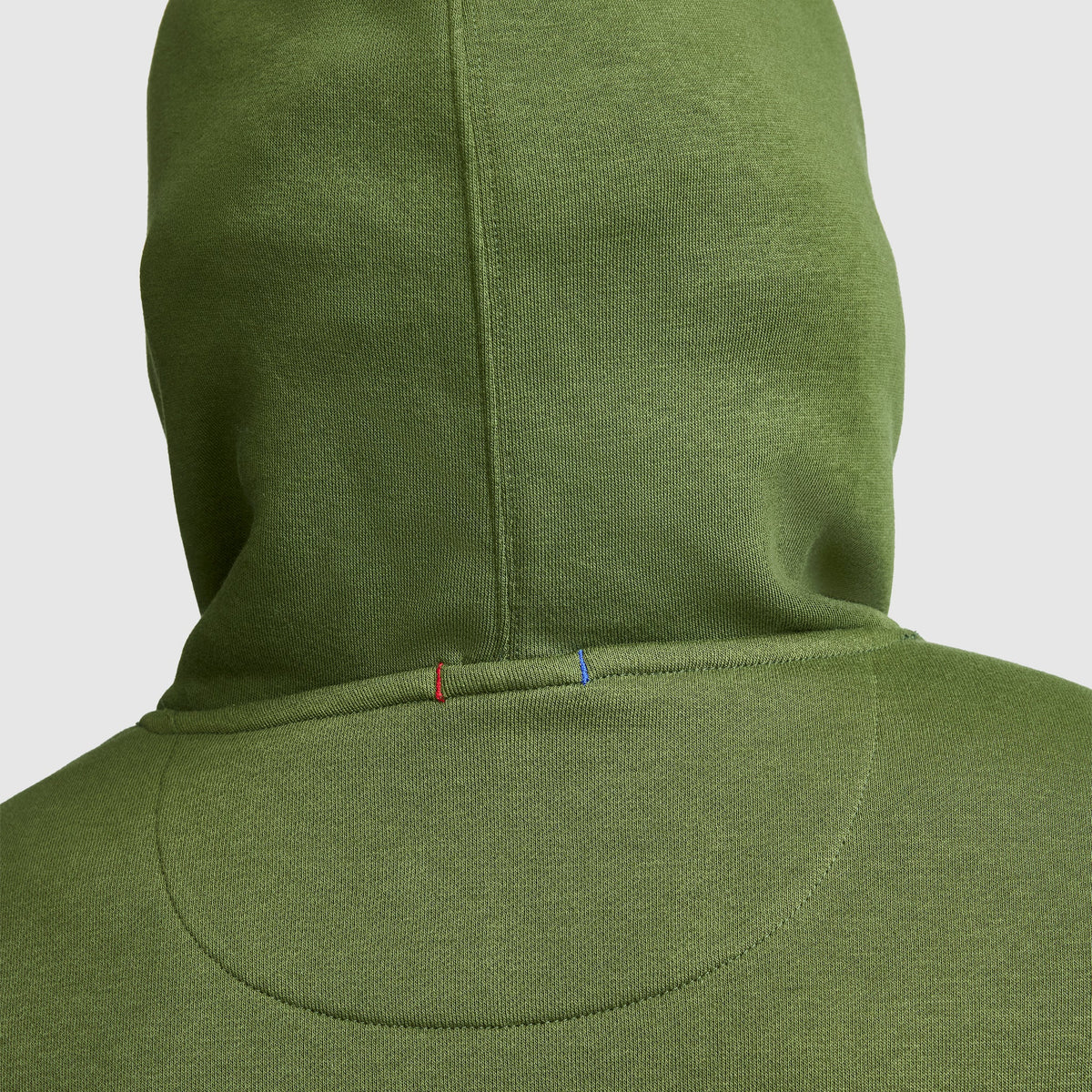 The back view of the Champion Powerblend Hoodie, Full Script Logo features a seam adorned with small red and blue stitches near the neckline, set against a plain light background.