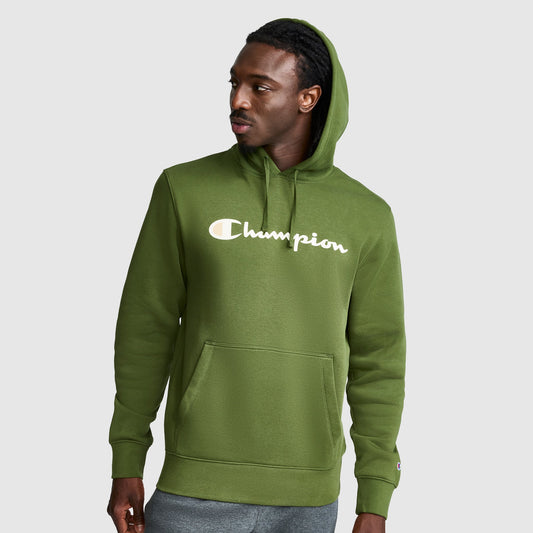 A man wearing a green Champion Powerblend Hoodie, Full Script Logo, featuring a front pocket and hood, looks to his left against a plain light gray background.