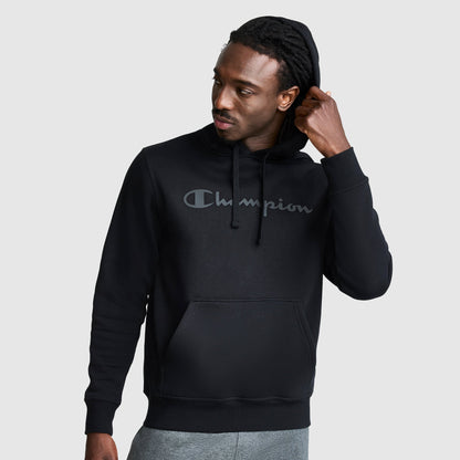 A person wearing a black Champion Powerblend Hoodie, Tonal Script Logo featuring a classic script logo on the chest and a front pouch pocket.