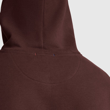 Close-up of the back of a men’s Champion Powerblend Hoodie, Tonal Script Logo, featuring the hood and upper back. Two small stitches—one red and one blue—are visible near the seam on this fleece hoodie. The background is light gray.