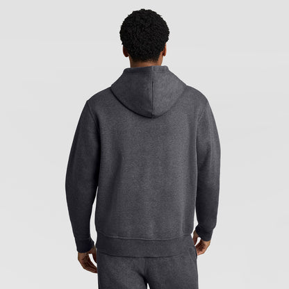 A person wearing the Champion Powerblend Hoodie, C Logo in dark gray, with matching sweatpants, is standing with their back to the camera against a plain light gray background.