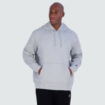 A man wearing a grey Champion Powerblend Hoodie, C Logo - Big & Tall featuring a hooded design, a front kangaroo pocket, and a small logo on the sleeve.
