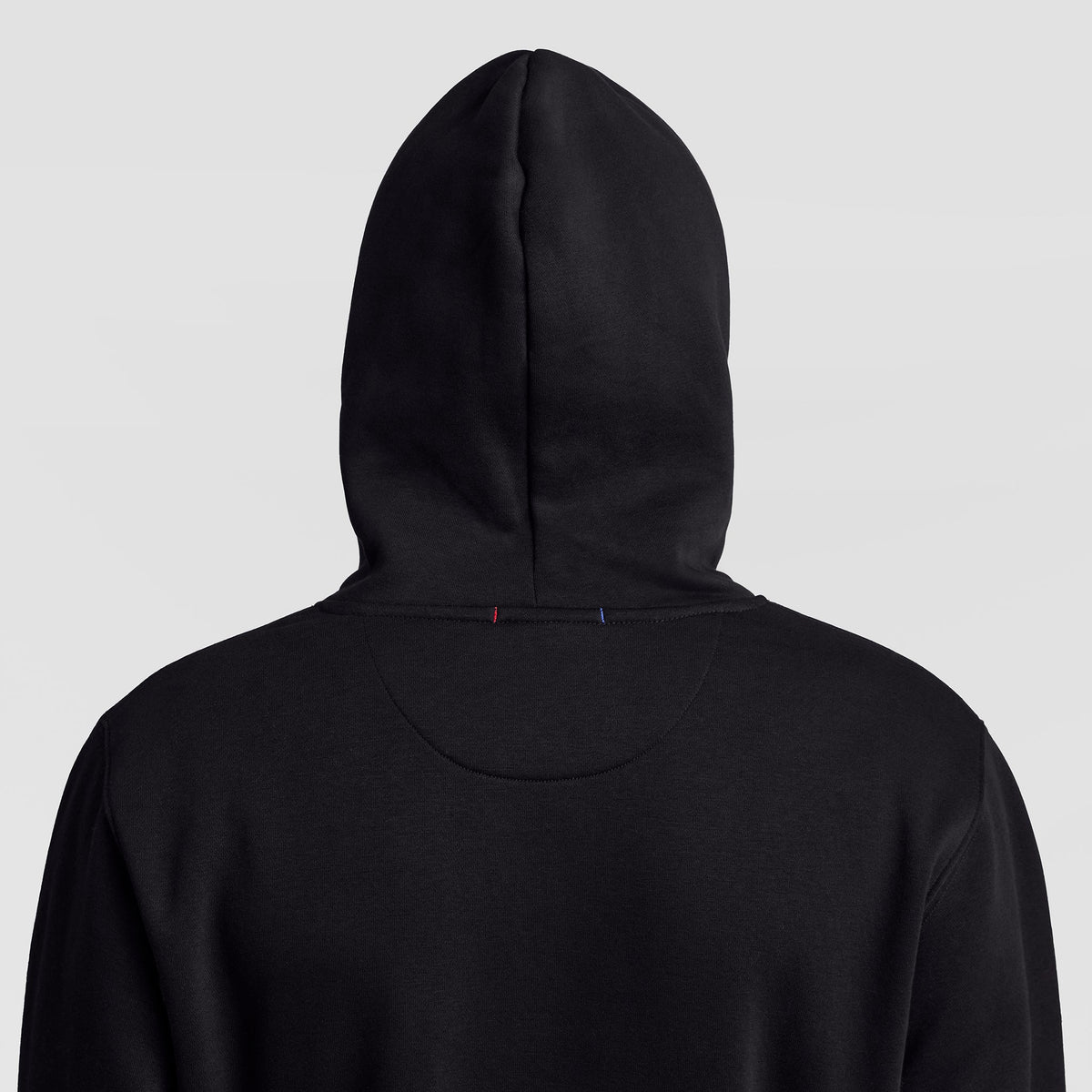 A person wearing a black Champion Powerblend Hoodie, C Logo, with the hood up, shown from behind against a light gray background.
