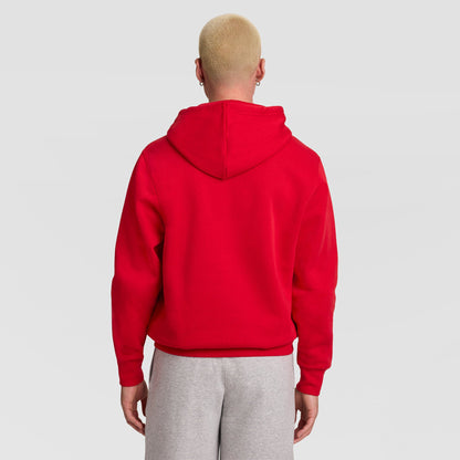 A person with short blond hair is shown from behind, wearing a bright red Champion Powerblend Hoodie, C Logo, and light gray sweatpants, standing against a plain light gray background.