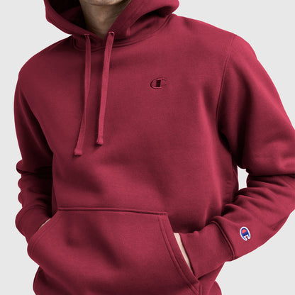 Model wearing a maroon Champion Powerblend Hoodie, C Logo with front pocket and logo on chest and sleeve, shown from shoulders to waist against a plain background.