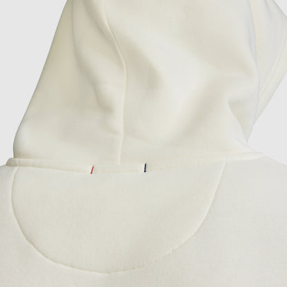 Close-up of the back of the cream-colored Champion Powerblend Hoodie, C Logo, highlighting the visible hood seam and small red and blue stitches near the neckline that showcase the classic fleece hoodie details.