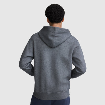 A person stands facing away with hands on hips, wearing a Champion Powerblend Full-Zip Hoodie, C Logo in dark gray with the hood down, paired with fleece sweatpants against a plain light gray background.