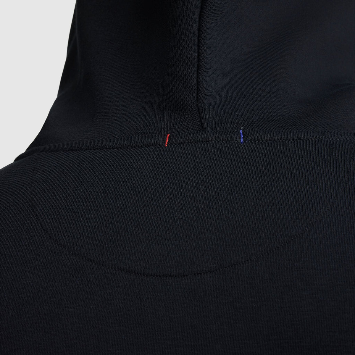 Close-up of the back of a Champion Powerblend Full-Zip Hoodie, C Logo – Big & Tall, highlighting detailed stitching with small red and blue thread accents near the neck area.