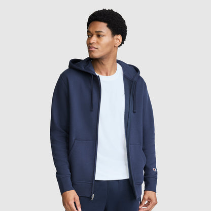 A person wearing a navy blue Champion Powerblend Full-Zip Hoodie, C Logo, with a small logo on the left cuff.
