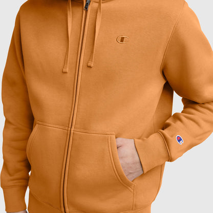 A person wearing the Champion Powerblend Full-Zip Hoodie, C Logo in orange has one hand in the front pocket. The iconic Champion logo appears on both the chest and sleeve, showcasing this comfortable men’s full-zip sweatshirt.