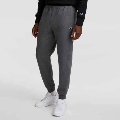 A person wearing Champion Powerblend Joggers, C Logo in dark gray and a black Champion sweatshirt stands against a plain white background. The Champion logo appears on both the joggers and the sweatshirt.