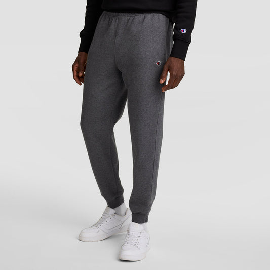 A person wearing Champion Powerblend Joggers, C Logo in dark gray and a black Champion sweatshirt stands against a plain white background. The Champion logo appears on both the joggers and the sweatshirt.