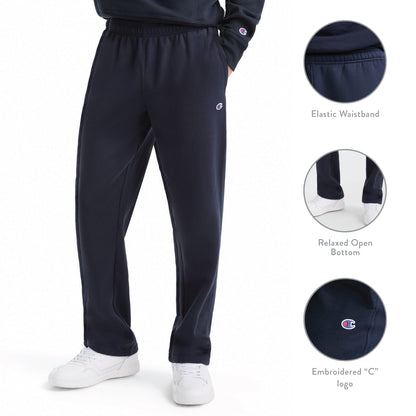 A person is wearing Champion Powerblend Sweatpants, Open Hem, C Logo in navy blue. These men’s sweatpants feature an elastic waistband, relaxed open bottom, and a small embroidered C logo. Crafted from a soft cotton blend for comfort and style, the design includes insets highlighting the waistband, pant hem, and logo details. White sneakers complete the look.
