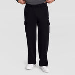 A person wears Champion’s Fleece Cargo Pant with a C Logo in black and pairs them with white sneakers, standing against a plain light gray background with their hands tucked into the waistband of the pants.