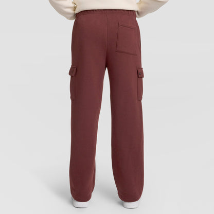 A person wearing Champion Fleece Cargo Pant, C Logo in maroon, styled as streetwear with side and back pockets, stands against a plain light background. Only the lower half of the body is visible.