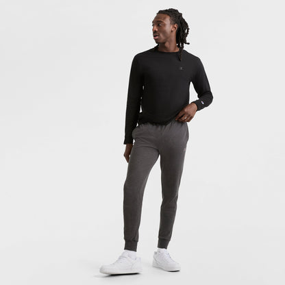 A man in a black shirt and Champion Lightweight Lounge Joggers with an elastic drawcord waistband and C Logo.
