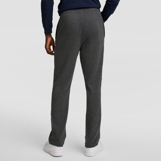 A person stands facing away, wearing Champion Lightweight Lounge Pants with an open hem and C logo, paired with a navy long-sleeve top and white sneakers against a plain light background.