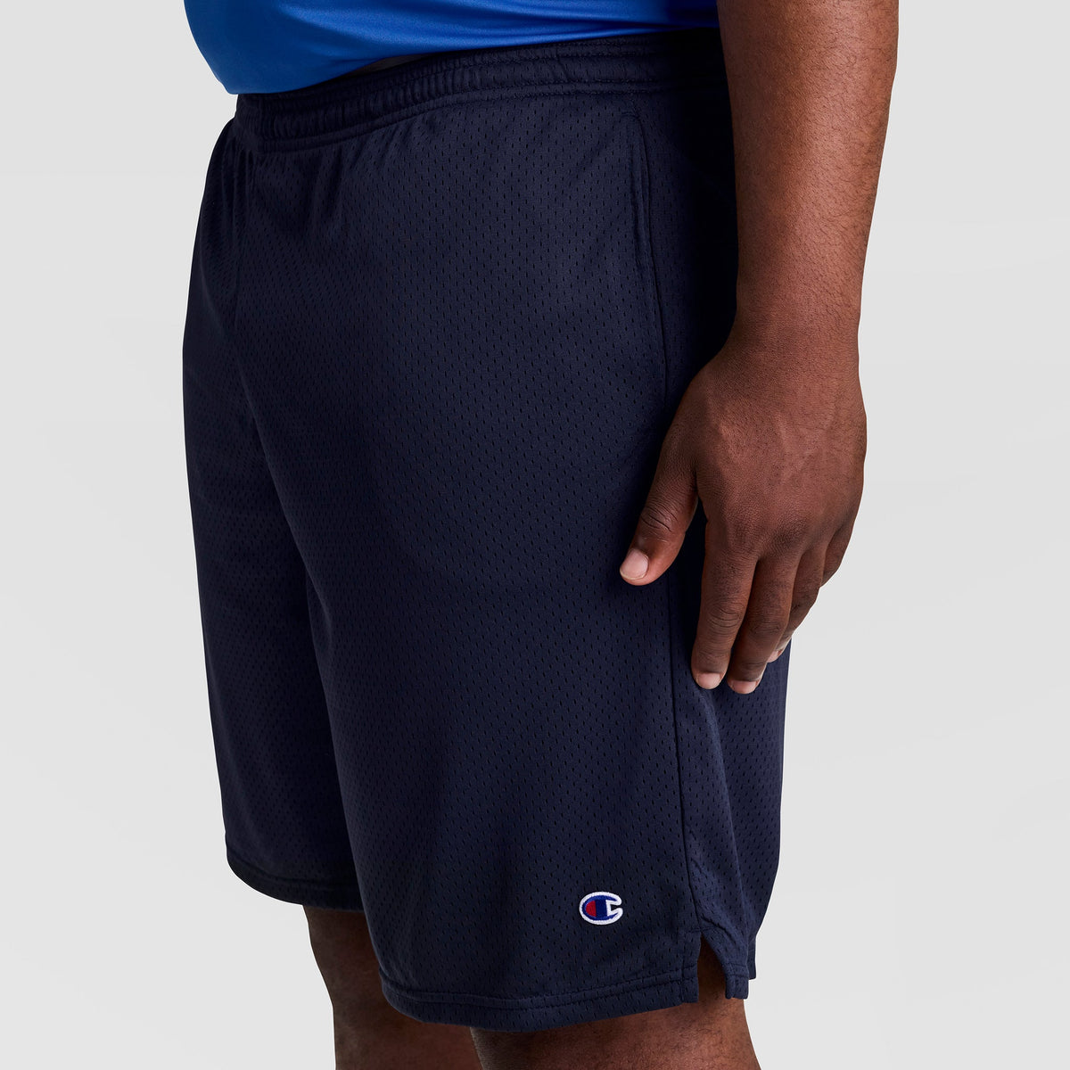 A person models the Champion 9" Classic Mesh Shorts, C Logo - Big & Tall in navy blue, standing against a plain light background with only the lower torso and upper legs shown.