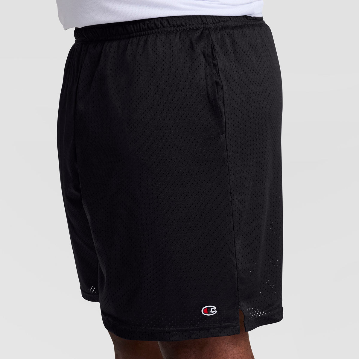 A person models Champion 9" Classic Mesh Shorts, C Logo – Big & Tall in black, showing only the lower torso and upper legs against a plain background. The small Champion logo is visible near the hem.