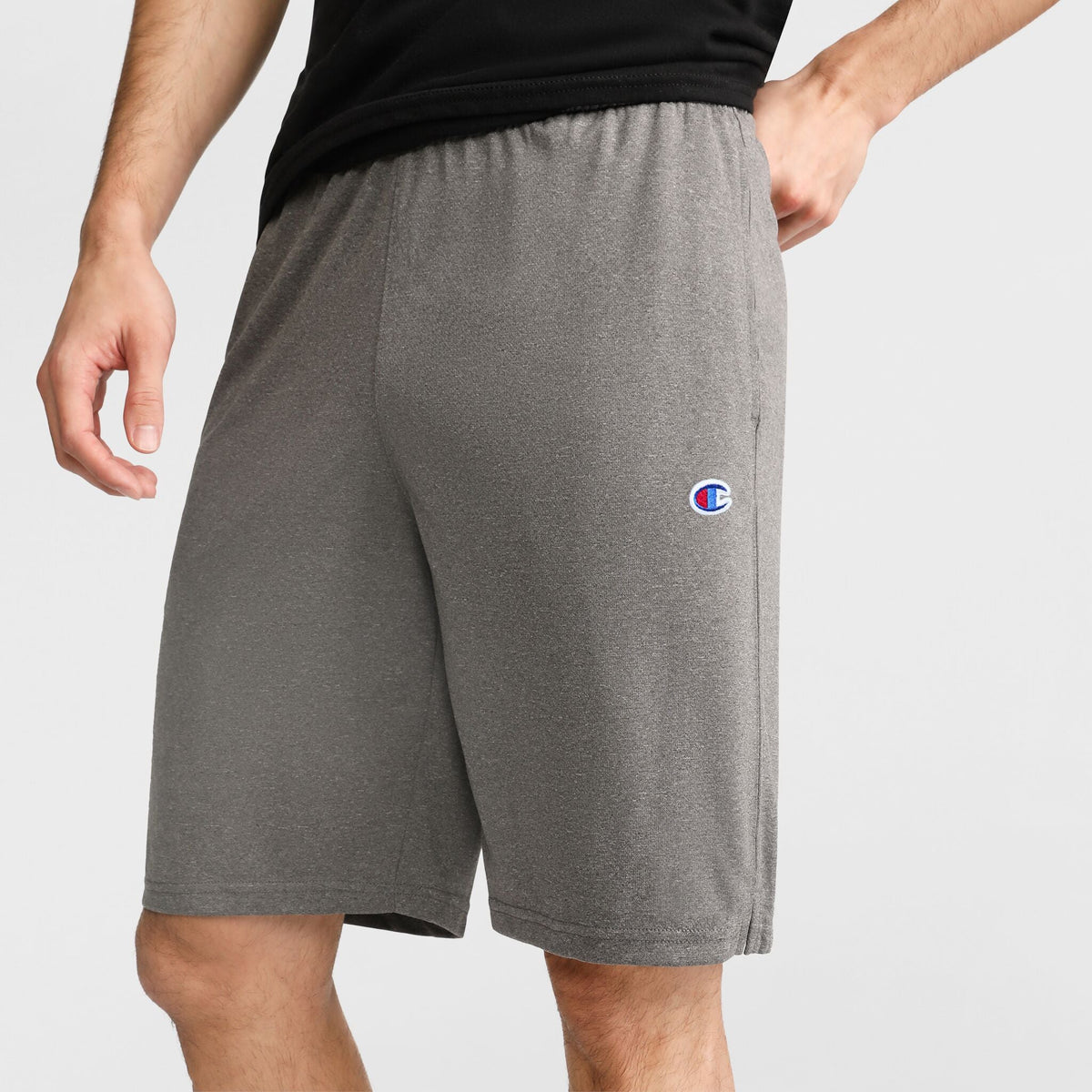 A person stands against a plain background, showcasing only their lower torso and upper legs while wearing Champion's 9" Lightweight Lounge Shorts with the C Patch Logo in gray. The Champion logo appears on the left thigh, emphasizing these comfortable shorts as an ideal choice for lounging or casual activities.