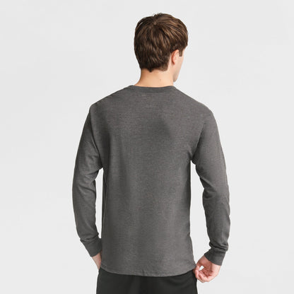 Seen from behind against a white background, a person with short brown hair wears the Champion Classic Long Sleeve T-Shirt, Embroidered C Logo, in dark gray and black pants.