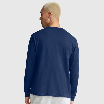 A person with short blond hair is shown from the back against a plain light gray background, wearing light gray pants and a navy blue Champion Classic Long Sleeve T-Shirt featuring an embroidered C logo, crafted from a soft cotton blend.