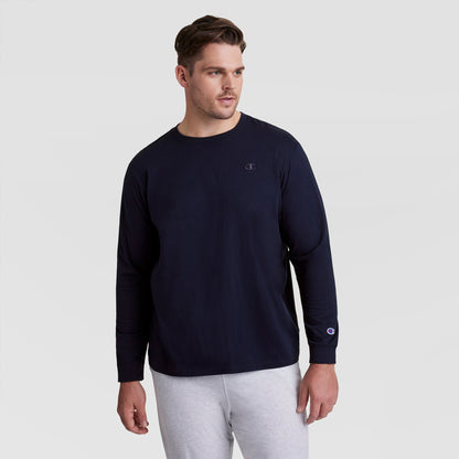 A man wearing a navy blue Champion Classic Long Sleeve T-Shirt with Embroidered C Logo (Big & Tall) stands against a plain light gray background, looking slightly to his left.