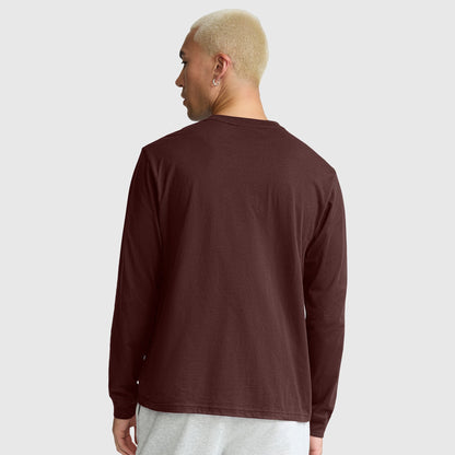 A person with short blond hair, seen from behind and standing against a plain light gray background, is wearing a Champion Classic Long Sleeve T-Shirt with an embroidered C logo in maroon and light gray pants.