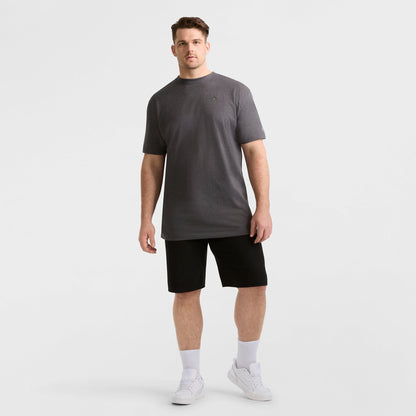 A man faces forward against a white background wearing the Champion Classic T-Shirt, C Logo - Big & Tall in gray, paired with black shorts, white crew socks, and white sneakers. He stands in a relaxed posture.