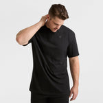 A man models the Champion Classic T-Shirt, C Logo - Big & Tall with black pants, standing against a white background while looking down and touching the back of his neck.