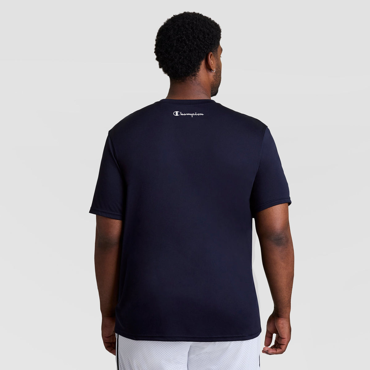 Back view of a person wearing a navy blue Champion Sport T-Shirt, Reflective C Logo - Big & Tall, featuring a small logo printed on the back of the neck.