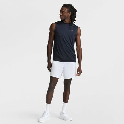 A man stands against a plain white background wearing the Champion Sport Muscle Tank with Reflective C Logo, paired with white shorts, socks, and sneakers. He looks to the side with one hand relaxed and the other by his side.
