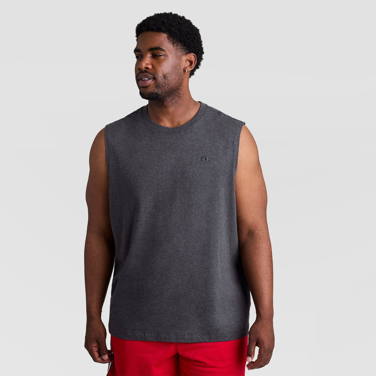 A man wearing a charcoal grey Champion Muscle Tank, C Logo - Big & Tall, a sleeveless muscle tee with a small logo on the chest.