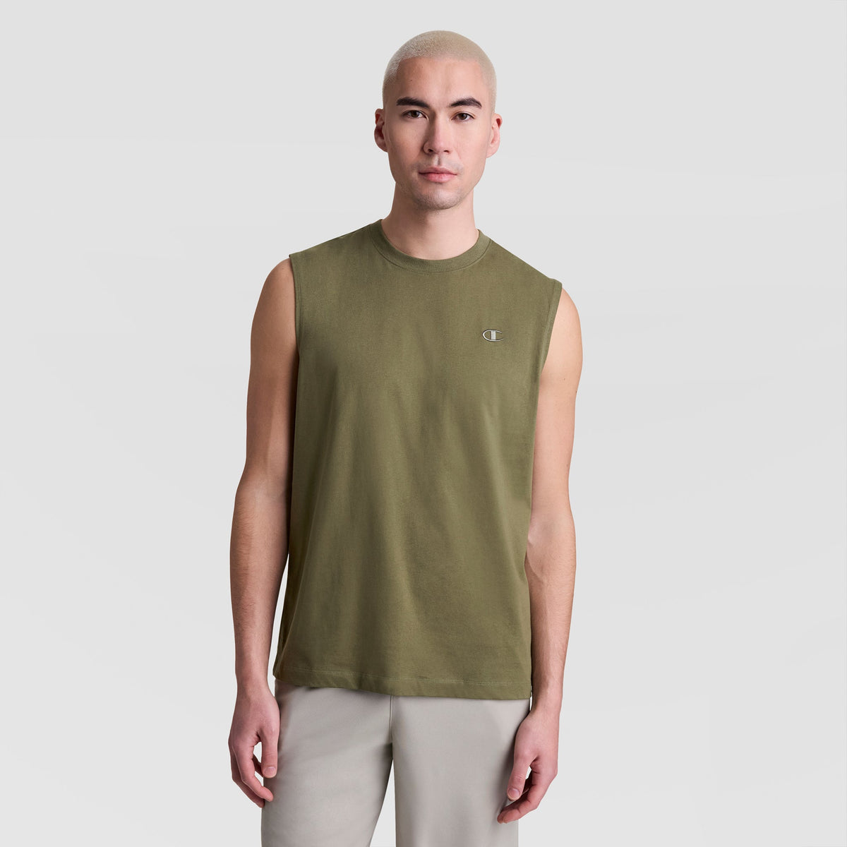 A person with short, light blonde hair wears a Champion Muscle Tank, C Logo in olive green and light gray pants, standing against a plain light gray background.