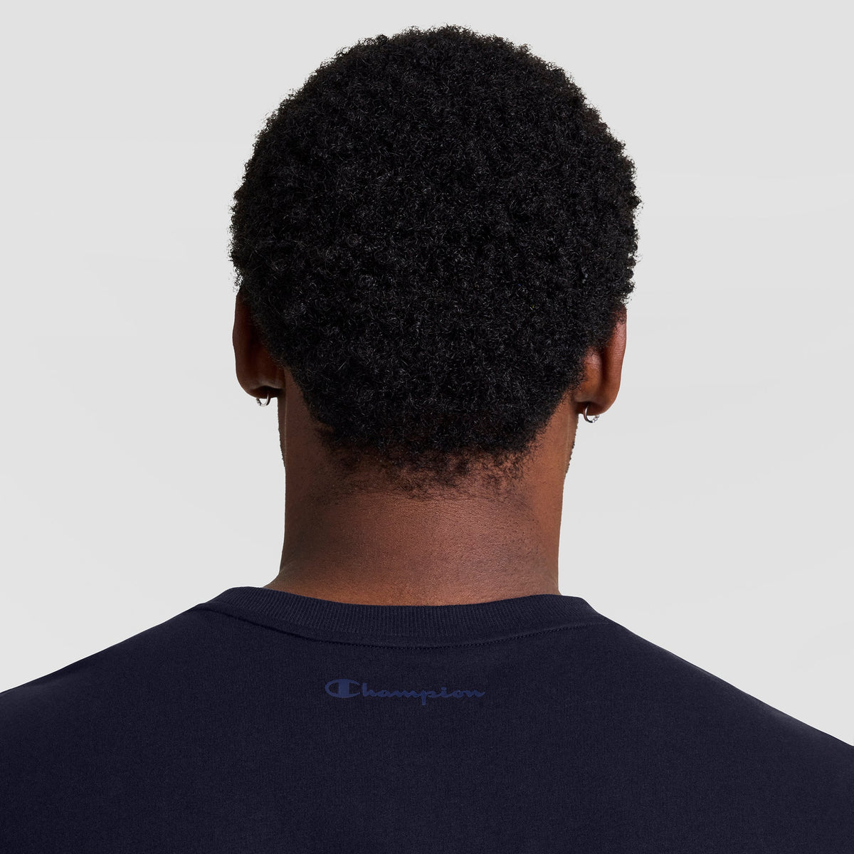 Back view of a person wearing a dark navy Champion Muscle Tank, C Logo - Big & Tall with a small logo printed on the center of the upper back.