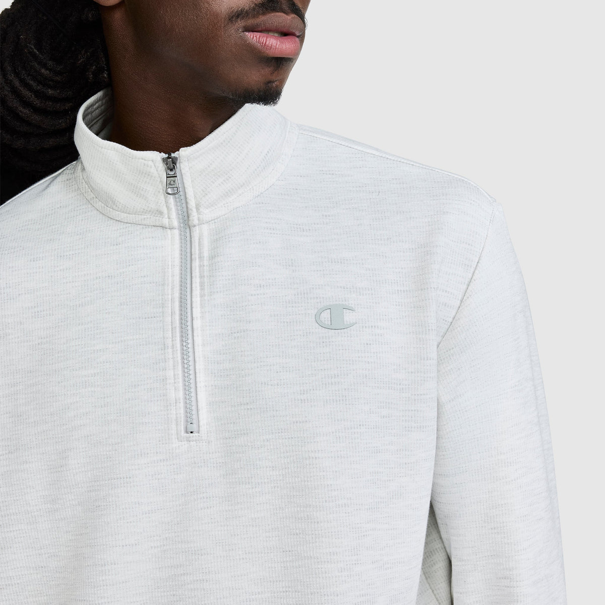 A person wearing the Champion Sport Long Sleeve 1/4 Zip Mockneck featuring the signature C logo on the chest, shown from shoulders to lips against a plain background.