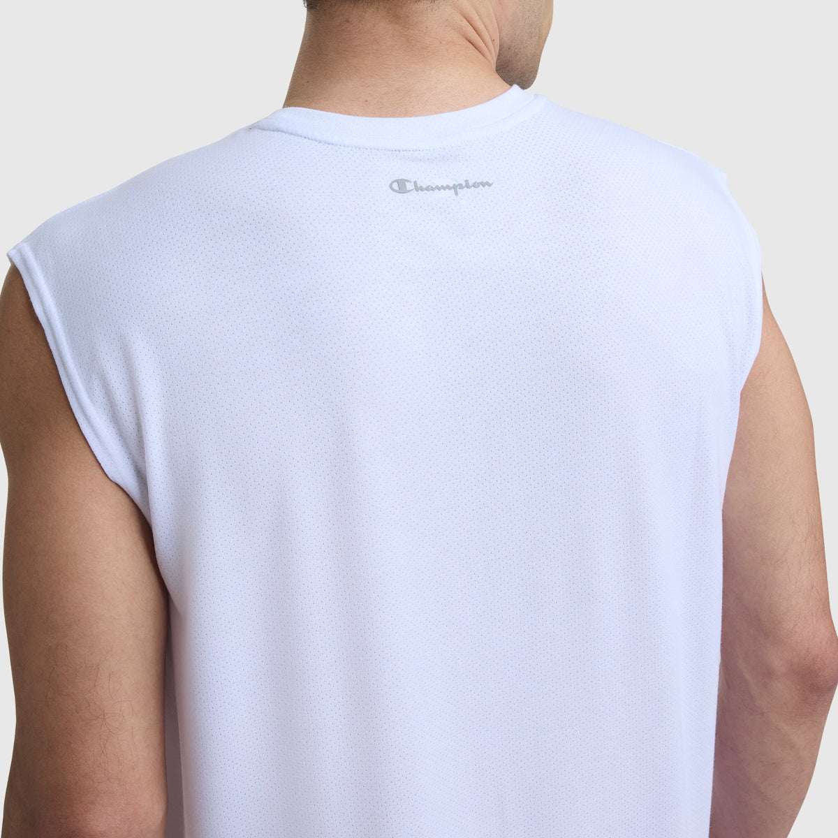 A person is seen from the back wearing the Champion Sport Crewneck Muscle Tee, Script Logo—a sleeveless white mesh shirt with a small gray Champion script logo by the neckline.